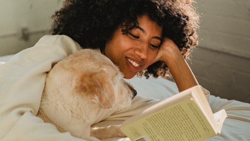 a woman reading a book with her dog