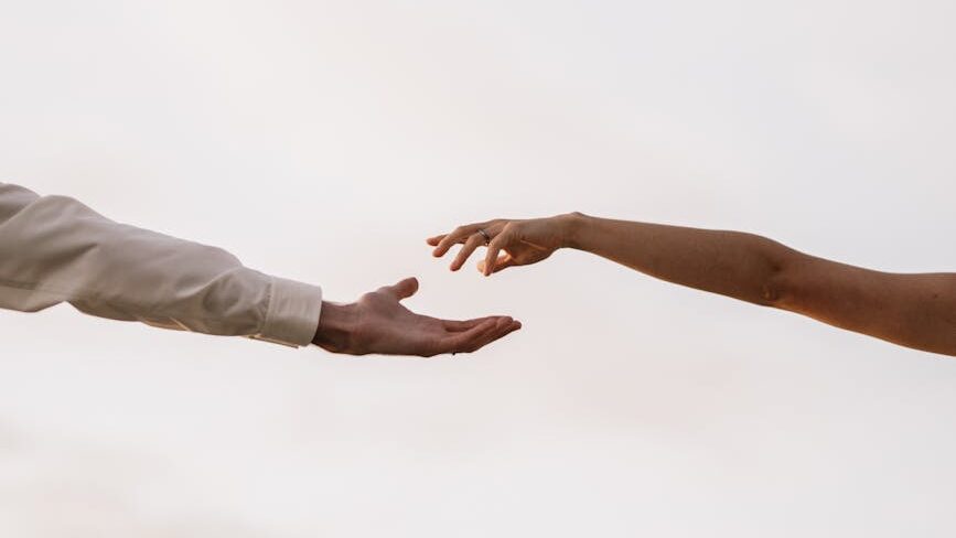 couple reaching out to each other against the sky